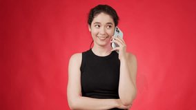 Casually dressed in black top positive and enthusiastic happy young brunette chatting on smartphone while laughing heartedly against pink background