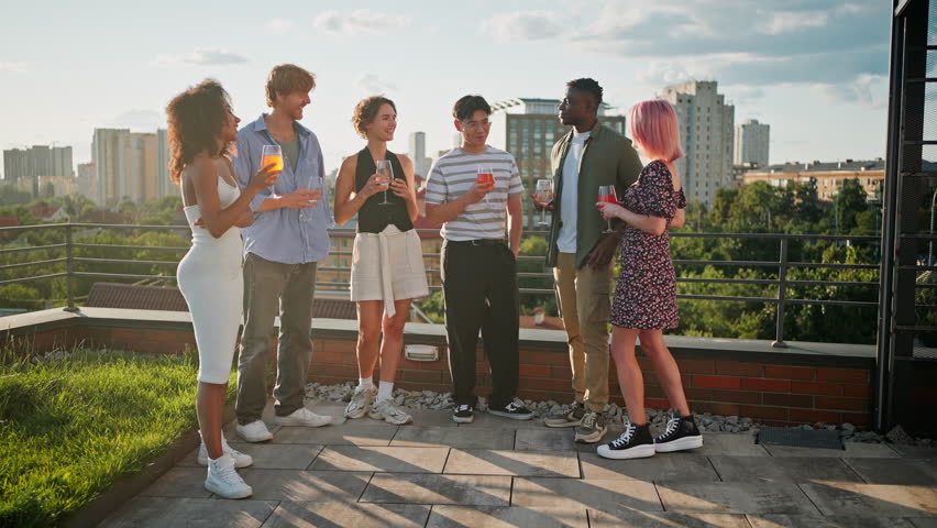 Full length portrait of young men and women relaxing together on summer terrace with drinks and talks. Multicultural friends in casual attire enjoying relaxing vibes in middle of working week. - Powered by Shutterstock - Get 15% off with code: PIKWIZARD15