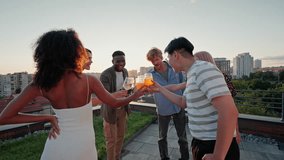 Company of multicultural good friends arranging reunion party at high-rise building rooftop with city panorama. Positive male and female young people clinking glasses with beverages and having fun. - Powered by Shutterstock - Get 15% off with code: PIKWIZARD15