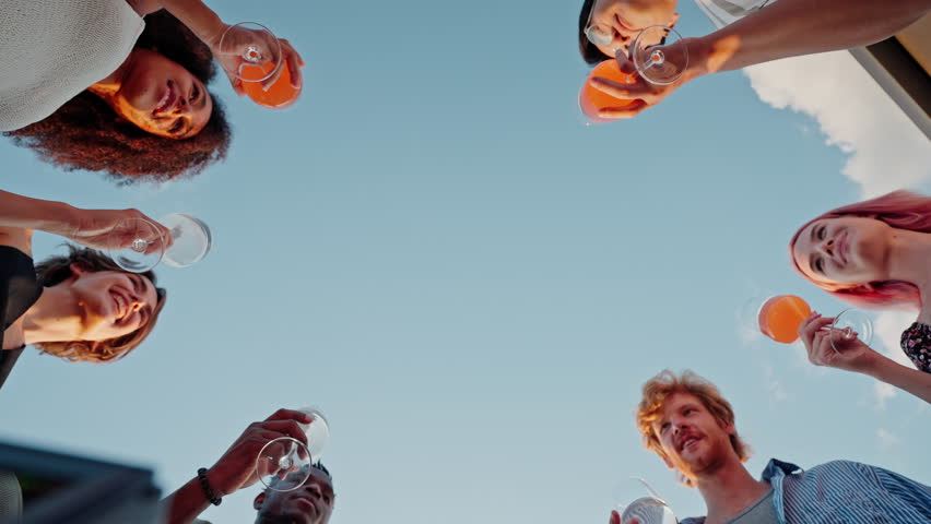 Bottom view of six multiracial colleagues clinking glasses with alcohol drinks during corporate party on open air. Happy people in classy outfits celebrating successful business deals. Royalty-Free Stock Footage #1107689161