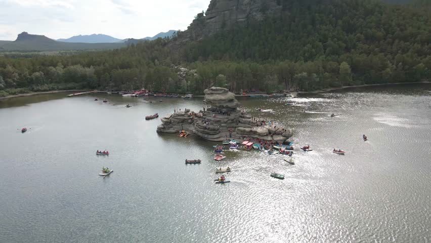 Boat trip on catamarans and boats.Stone island of Zhumbaktas in the middle of a mountain lake in Kazakhstan Borovoe.The rock in the middle of the water the Kazakh Sphinx.A lot of people on the water