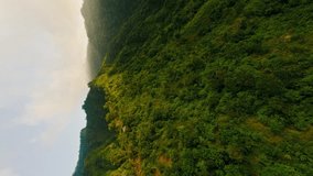 Vertical video. Aerial fpv sport drone raising view mountain range peaks landscape green plants in Asia. Scenery wild nature destination cinematic green hills steep slopes geology formation valley 4k