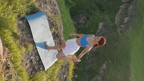 Vertical Video, Athletic Woman Doing Yoga Poses on Top Mountain During Sunset. Sports Girl Trains and Does Stretching Exercises in Mountains. Healthy Lifestyle, Zenism, Workout Concept. Slow Motion
