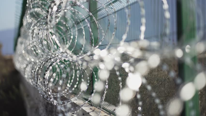 Dramatic scene of barbed wire fence on a prison wall, selective focus cinematic shot Royalty-Free Stock Footage #1107695245
