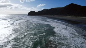 A flight from the south to the north along North Piha beach over the surf. 