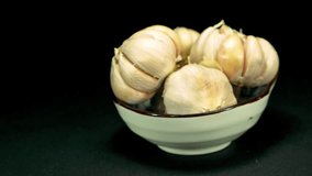 Garlic is part of the food that smells good. Garlic in a cup swirl around the black background