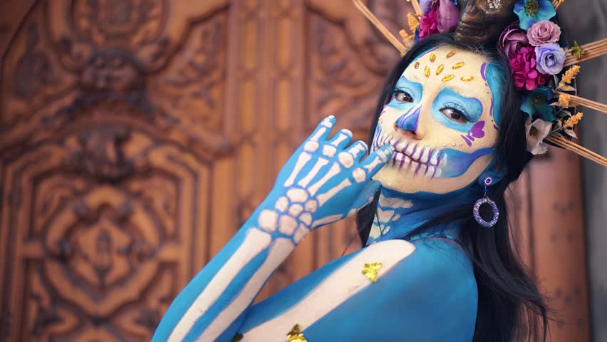 Dancer in costume for dia de los Muertos, woman with long dark hair in traditional costume and Mexico Catrina makeup standing near wooden ornamental door and holding skirt. Day of death Royalty-Free Stock Footage #1107696789