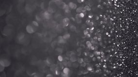 Black Glitter Background. Light bokeh, magic christmas lights. Magic dust, shiny texture, holiday lights, flying particles form a beautiful bokeh. Shining festive Christmas backdrop. Vertical Video