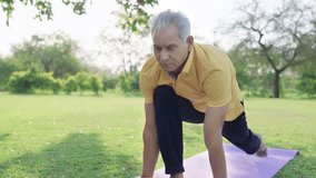 Fit Mature Grey haired Indian Asian Male or Active Senior old man Performing a Yoga asana or stretching exercise on mat in a Green Park in morning sunlight. Healthy lifestyle, outdoor fitness concept - Powered by Shutterstock - Get 15% off with code: PIKWIZARD15