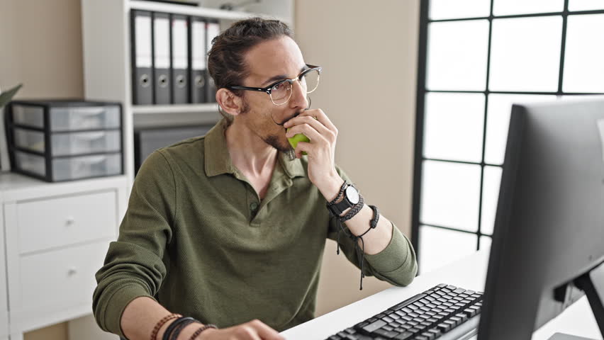 Young hispanic man business worker using smartphone eating apple at office - Powered by Shutterstock - Get 15% off with code: PIKWIZARD15