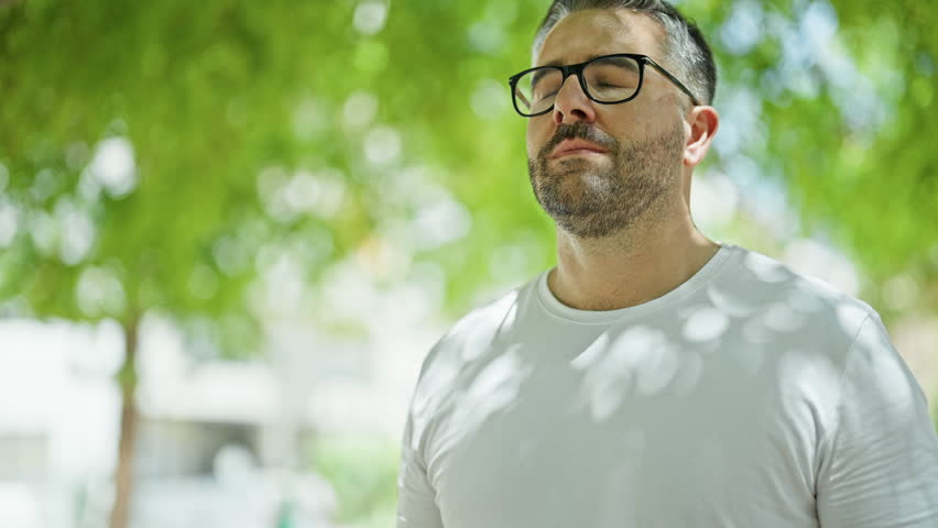 Grey-haired man smiling confident breathing at park