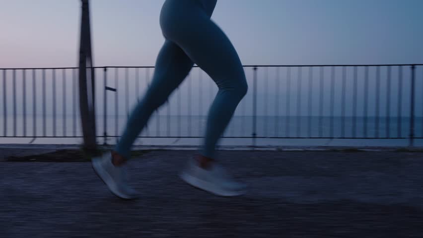 Woman running at nighttime. Young woman run sunrise seaside. Concept of health and lifestyle. Royalty-Free Stock Footage #1107710323
