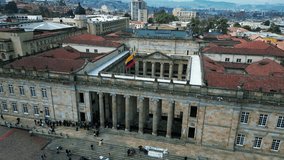 The drone is fluying around the capitol building with the colombian flag waving on top in Bogota Colombia Aerial Footage 4K