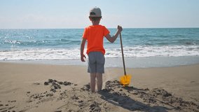 The boy playing with a shovel near the sea. 4k video footage 