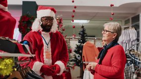 Retail assistant wearing Santa Claus costume helping senior client in shopping store find red blouse needed for xmas party attire. Worker assists elderly woman in fashion shop during Christmas season - Powered by Shutterstock - Get 15% off with code: PIKWIZARD15