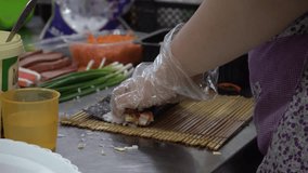 A Korean woman makes sushi in her restaurant kitchen. Learn the process in this step-by-step video in a proper sanitation