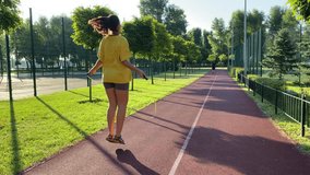 Vigorous multiracial young woman engages in morning workout at landscaped public park. She jumps rope boundless energy infusing day with vitality. Clear blue sky with golden sunlight. 360 degree video