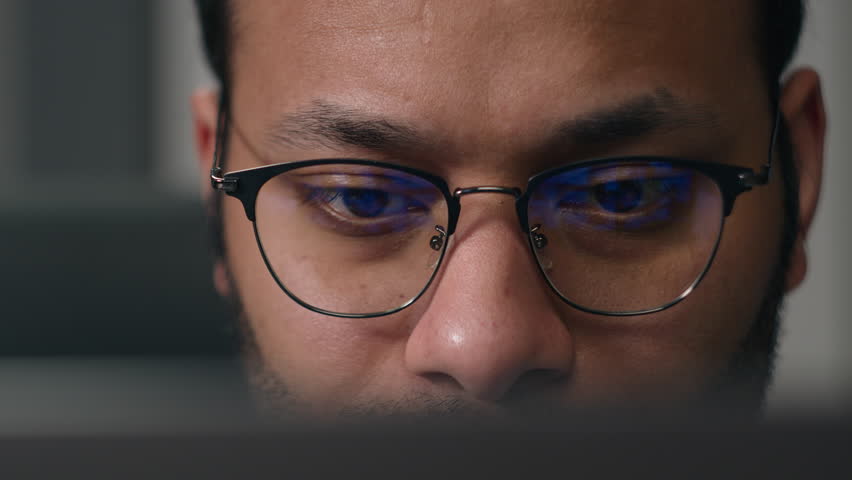 Close up concentrated focused male eyes in eyeglasses looking at laptop monitor screen light reflection in glasses man businessman at night programming codding with computer reducing eye strain vision Royalty-Free Stock Footage #1107717247