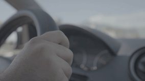 A driver's hands on a steering wheel, driving a car. Establishing shot. log footage.