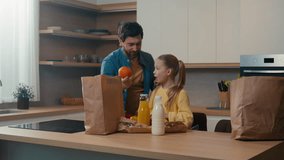 Happy family at kitchen home unpacking bag shopping purchase goods with milk bottle juice bread father dad give orange fruit vitamin to little daughter child kid girl food delivery service nutrition - Powered by Shutterstock - Get 15% off with code: PIKWIZARD15