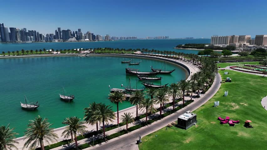 The drone is flying forward around the mia park harbour with lots of palmtrees and the skyline in the background on a sunny day in Doha Qatar Aerial Footage 4K | Shutterstock HD Video #1107724331