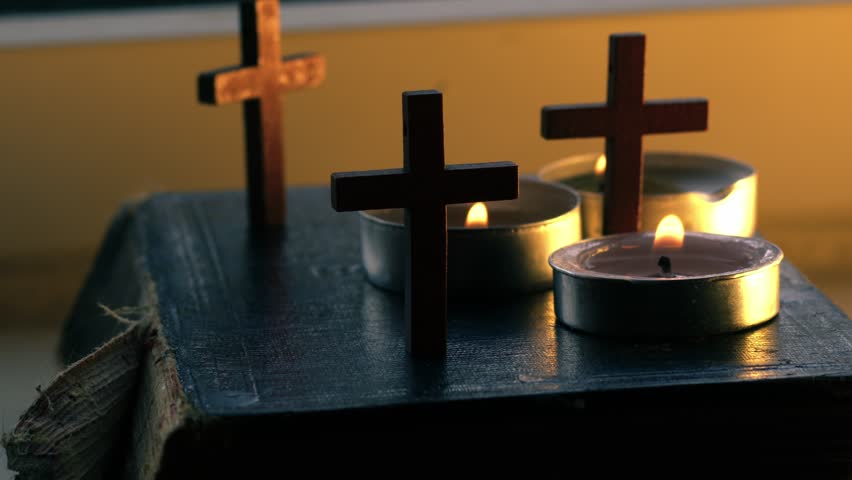 Holy bible with crucifix and tea light candles close up slow motion 4k shot shot selective focus