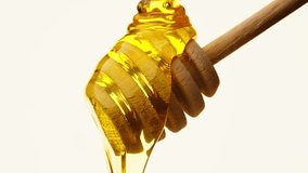 Golden Elixir: Sweet Honey Flowing from a Wooden Spoon on White Background