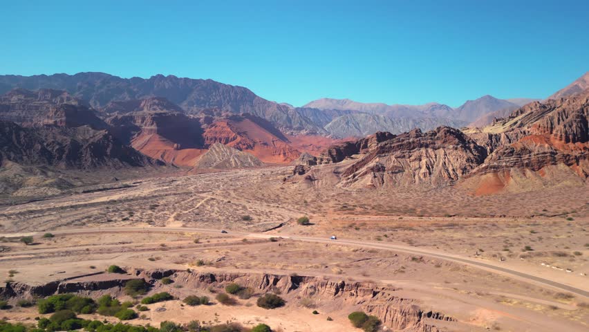 Aerial view drone flying over scenic red rocky mountains landscape with a clear blue sky. 