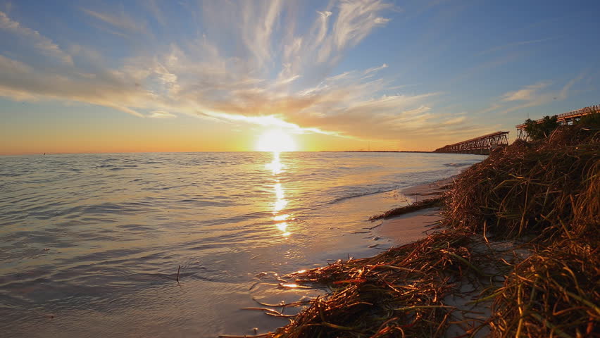 Sunset in the Florida Keys National Marine Sanctuary in Bahia Honda State Park. Simmering Atlantic Ocean waves lapping the shoreline. Whispy clouds moving as the sun sets in this time-lapse video 
