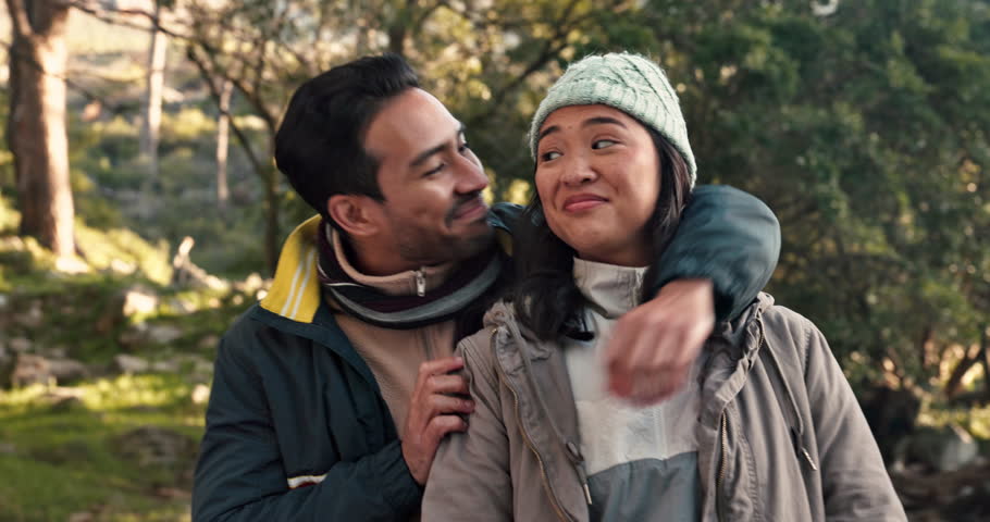 Hiking, couple and hug outdoor view in woods with freedom on a backpack travel journey in nature park. Trekking, fitness and wellness with young people relax on a adventure in the forest with smile