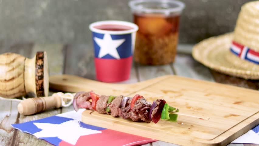 Fiestas Patrias Chile September 18, Independence Day. Empanadas, Anticuchos, mote con huesillo, chicha or wine, Sombrero, huaso, chupallas, straw and emboque, on wooden table with flag and copy space