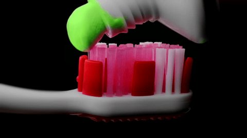 Tooth paste and brush. Applying green toothpaste on red toothbrush against black background in slow-motion. Adlı Stok Video