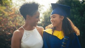 Proud mother celebrating with teenage daughter wearing graduation robes outdoors - shot in slow motion - Powered by Shutterstock - Get 15% off with code: PIKWIZARD15