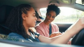 Teenage girl in car having driving lesson from female instructor or parent with digital tablet - shot in slow motion - Powered by Shutterstock - Get 15% off with code: PIKWIZARD15
