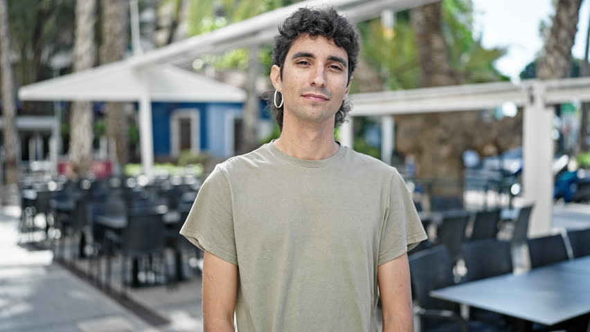 Young hispanic man smiling confident doing ok sign with thumbs up at coffee shop terrace