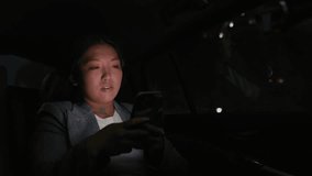 Business Chinese woman driving in a taxi and browsing phone at night. Shot with RED helium camera in 8K.  