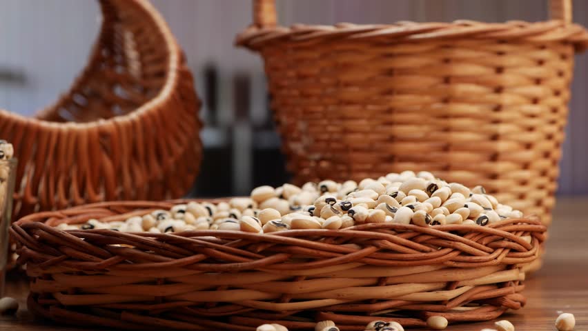 There is a basket of white beans in a brown basket, with brown handles
