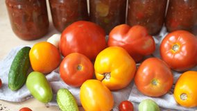 tomatoes are red and yellow, large and small spices cucumbers and garlic on a wooden table against the background of glass jars with canned vegetables. The concept of preparing blanks for the winter 