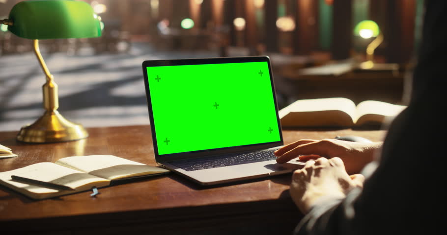 College Student Using Laptop Computer with Green Screen Mock Up Chroma Key Display to Study in a Classic Library. Anonymous Person Learning Online, Browsing Internet, Getting Ready for Exams Royalty-Free Stock Footage #1107760561