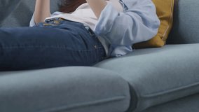 Close Up Of Asian Teen Girl Having Video Call On Smartphone While Lying On Sofa In The Living Room At Home. Waving Hands, Smiling, And Speaking
