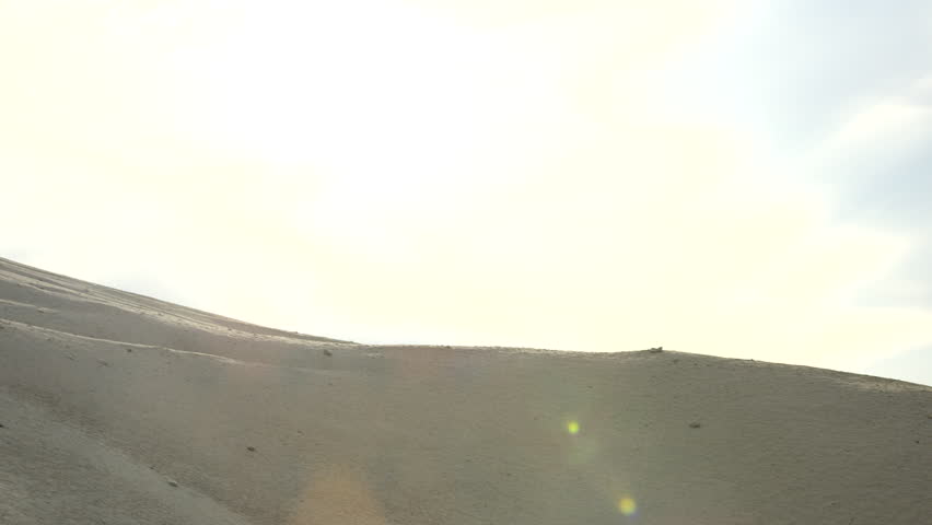 Motocross dirt biker catches air over side of sand dune at abandoned sand quarry