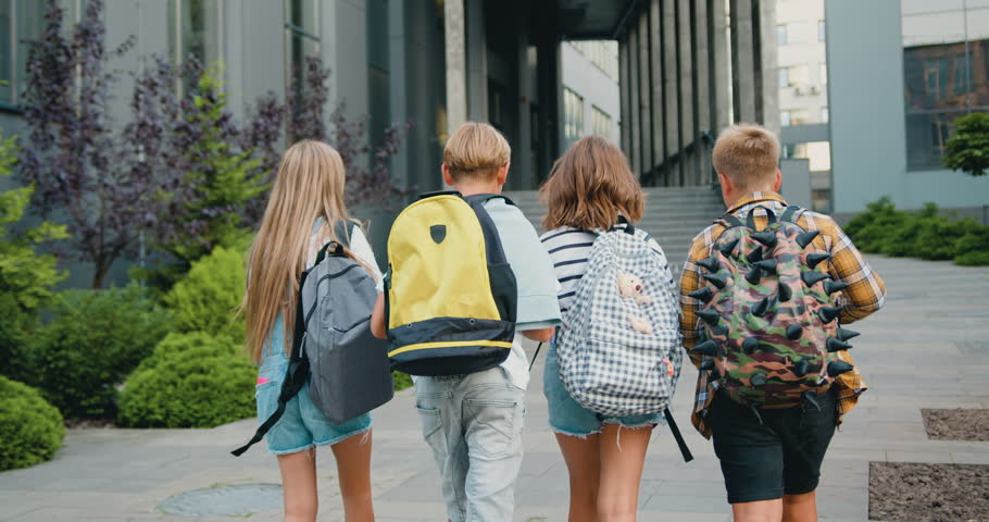 Group of cheerful energetic students child girl boy go to modern campus school with school backpacks. Kids meet each other in front of school. Back to school education kids concept. Royalty-Free Stock Footage #1107763439