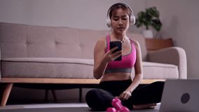 Young asian woman use laptop to listening music after watching fitness video to doing exercise