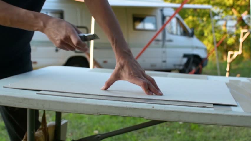 Female Graphic Designer Cuts The Cardboard With A Scalpel.
