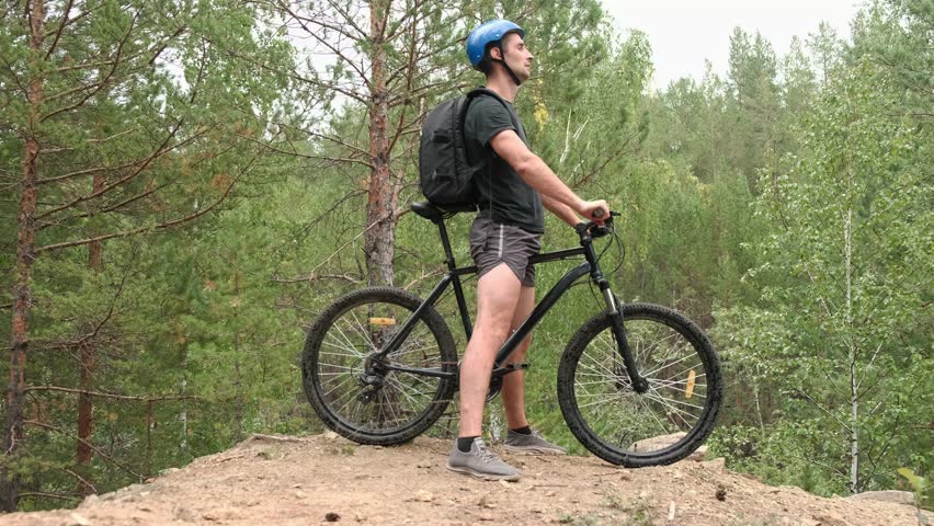 mountain bike.A cyclist in sportswear and a protective helmet climbed a mountain and enjoys nature.Slow motion.Off-road cycling