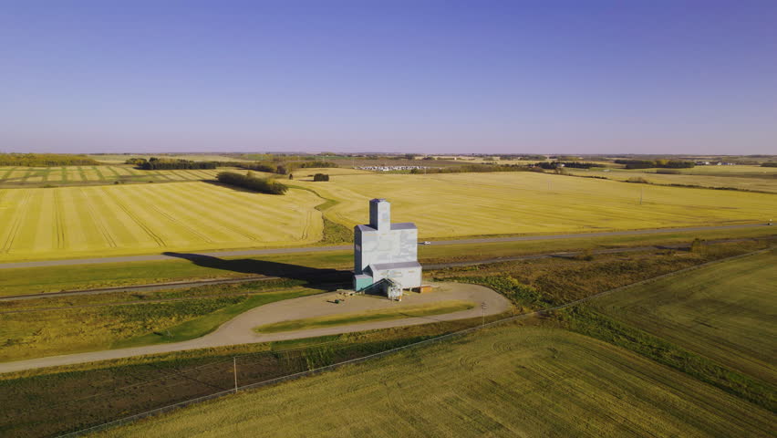 Aerial view grain elevator standing out between farm land. Alberta prairies