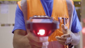 Warehouse worker holding barcode scanner and using management system close up. Storehouse employee in safety vest holding handheld bar code reader device closeup - Powered by Shutterstock - Get 15% off with code: PIKWIZARD15