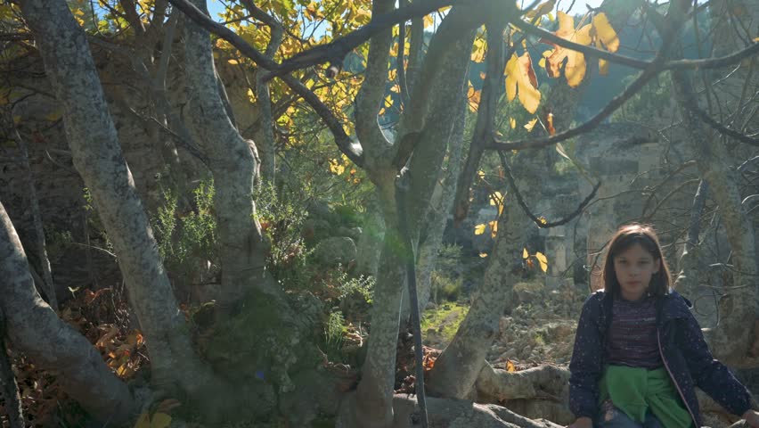 Girl swinging her legs and smiling sitting on the tree. 4k video footage UHD 3840x2160
