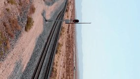 Aerial view driving through the gobi desert. Transmongol Railway. Huge freight train passing through Californian desert. It is the longest train in the world. Aerial vertical video background. 