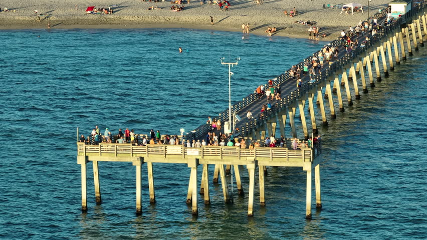 People enjoying vacation time on Venice fishing pier in Florida. Seaside summer activities on fresh air